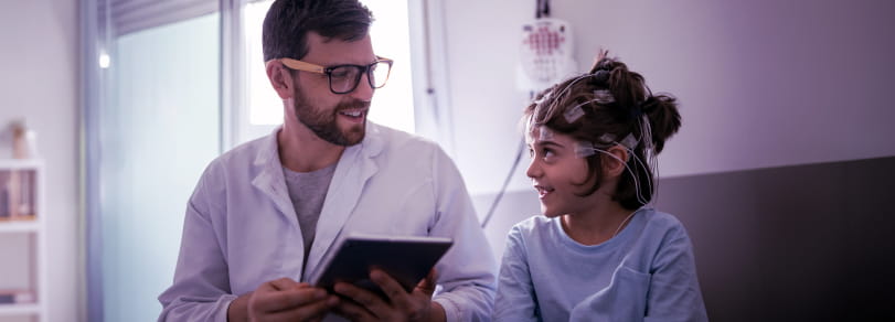A friendly healthcare provider talks about a medical procedure with a smiling child
