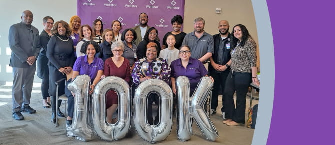 Photo of team with balloons reading "100K"