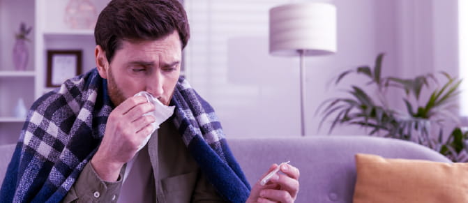 Person blowing nose and holding thermometer