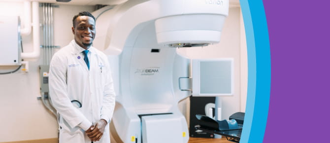 Dr. Nasarachi Onyeuku, a radiation oncologist at Wellstar, standing with one of the two TrueBeam linear accelerators in use for cancer care at Wellstar Cobb Cancer Center
