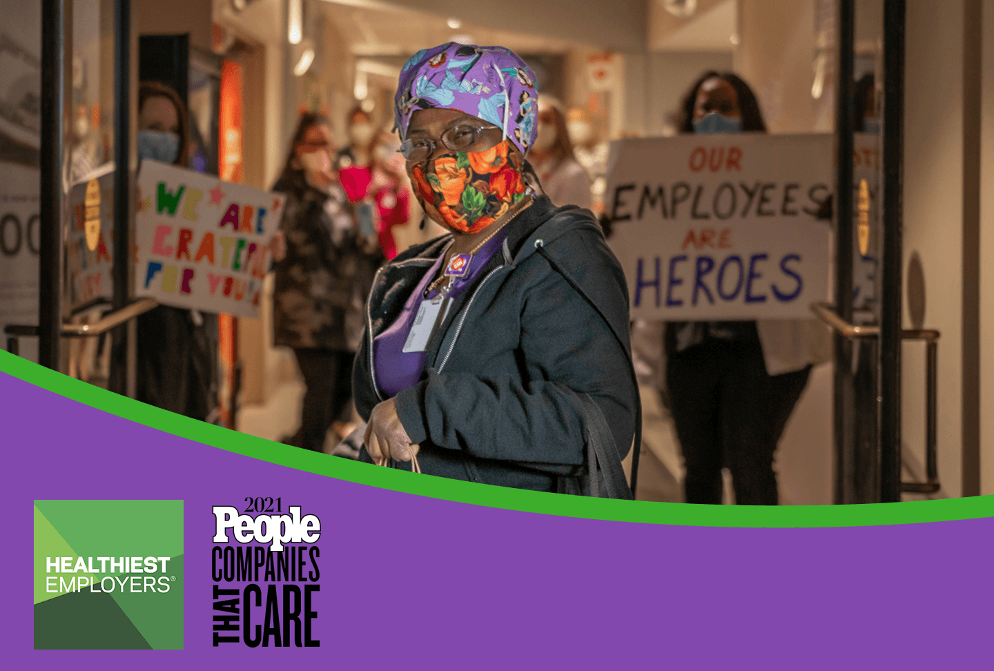 Team member in mask, support signs in background. Healthiest Employers and Companies That Care logos.