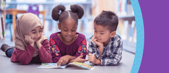 Three young children read a book together