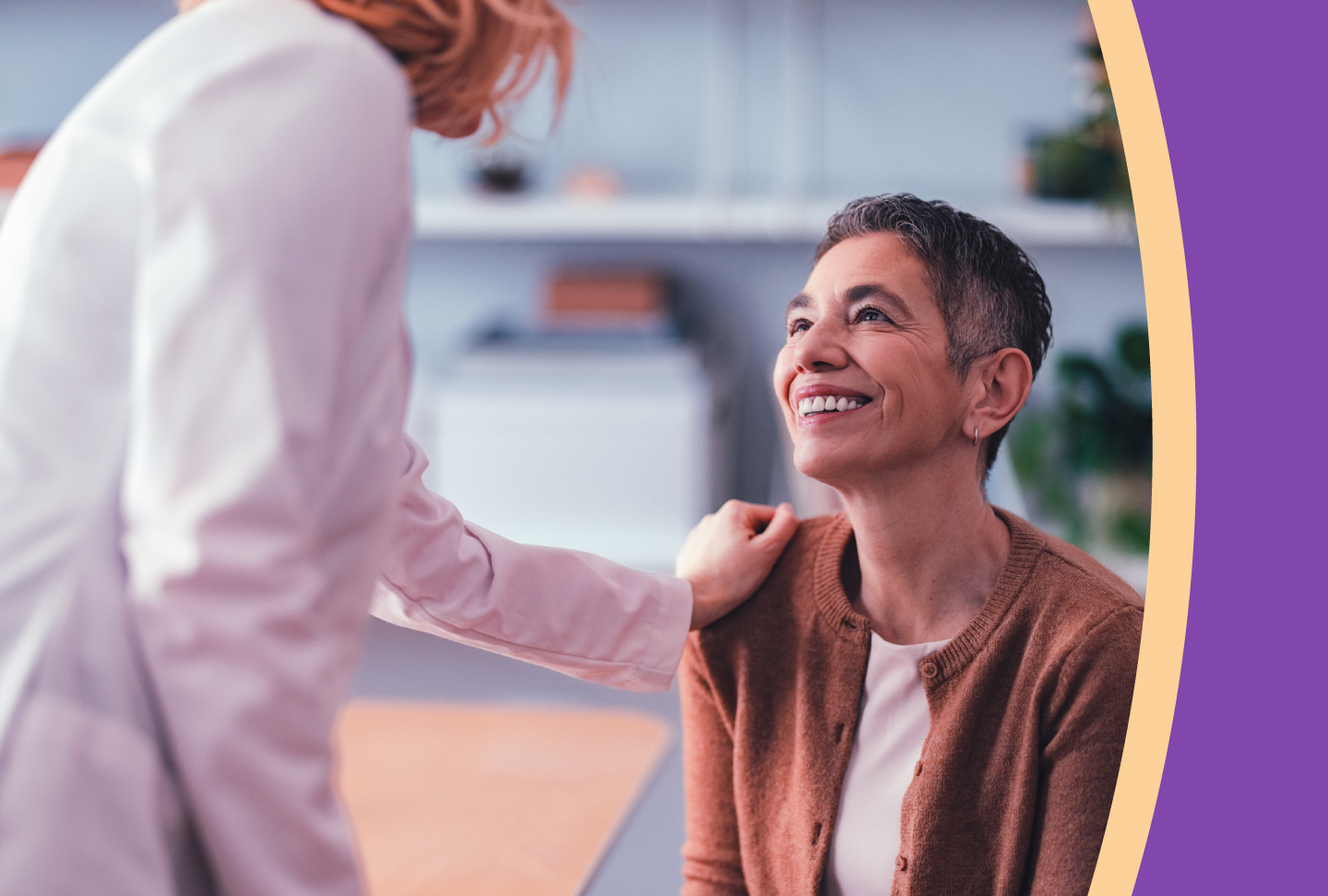 Care provider shows compassion for a patient with a gentle shoulder touch and the patient returns a genuine smile.