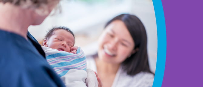 Healthcare provider hands a sleeping infant to a smiling mother