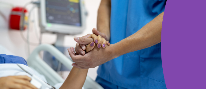 A healthcare provider holds the hand of her patient to encourage and comfort her