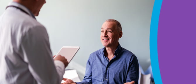 A healthcare provider shares news with a smiling man.