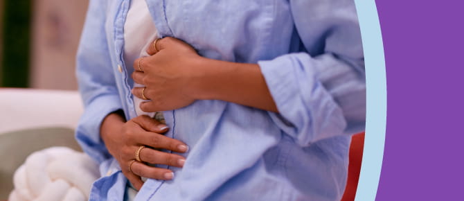 A woman holds both hands to her stomach in pain