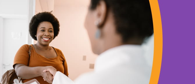 A smiling patient shakes hands with her healthcare provider.