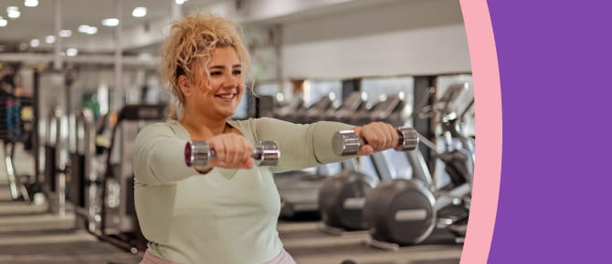 A young woman lifts weights in the gym