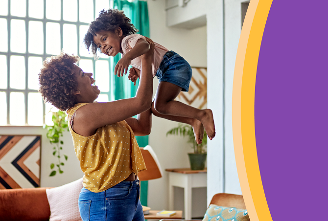 Mother smiling and lifting child up in the air.