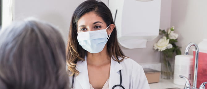A doctor consulting her patient while wearing a face mask