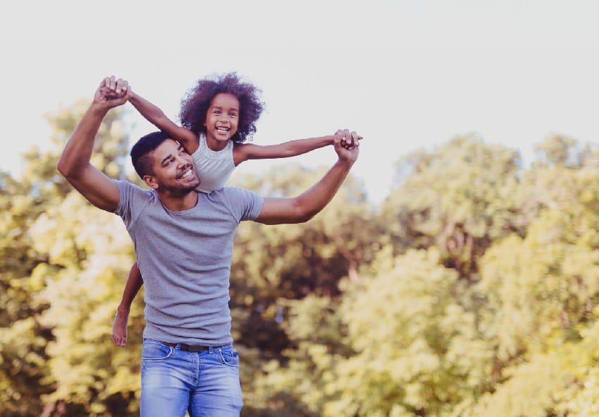 Dad holding holding daughter up on his shoulders with the Wellstar logo on the bottom
