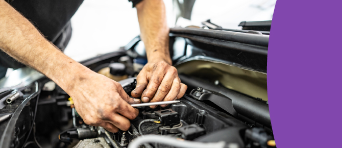 Close up of man’s hands working on vehicle engine.
