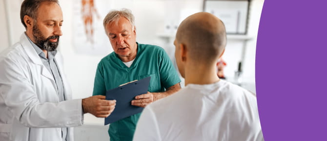 Male and female head and neck cancer specialists stand together looking at a chart and discussing the best treatment for a complex case of head and neck cancer.