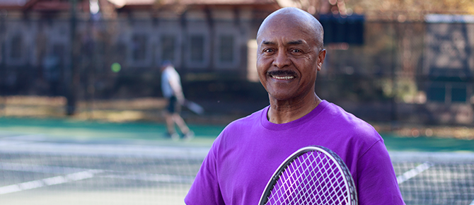 Ulysses Price smiling with his tennis racquet.
