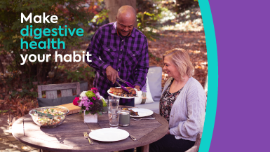 People at table outside serving food. Text reads "Make digestive health your habit"