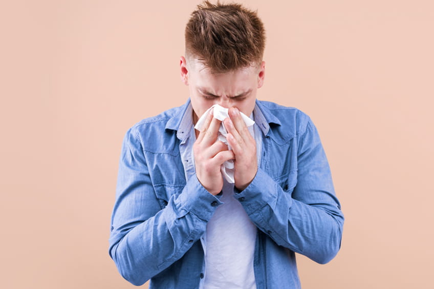 Photo of a man blowing his nose.