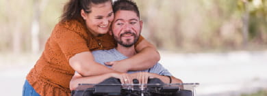 Woman hugging a man in a motorized wheelchair as both smile