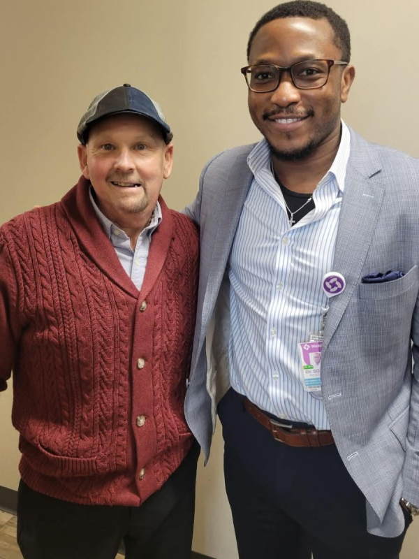 David Butler stands, smiling, with Dr. Fiyin Sokoya, a dual board-certified head and neck cancer specialist and facial plastic surgeon at Wellstar.