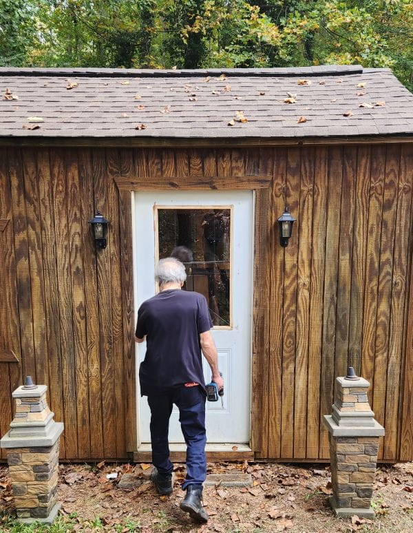 Billy enters his shed where he stores tools for his projects.